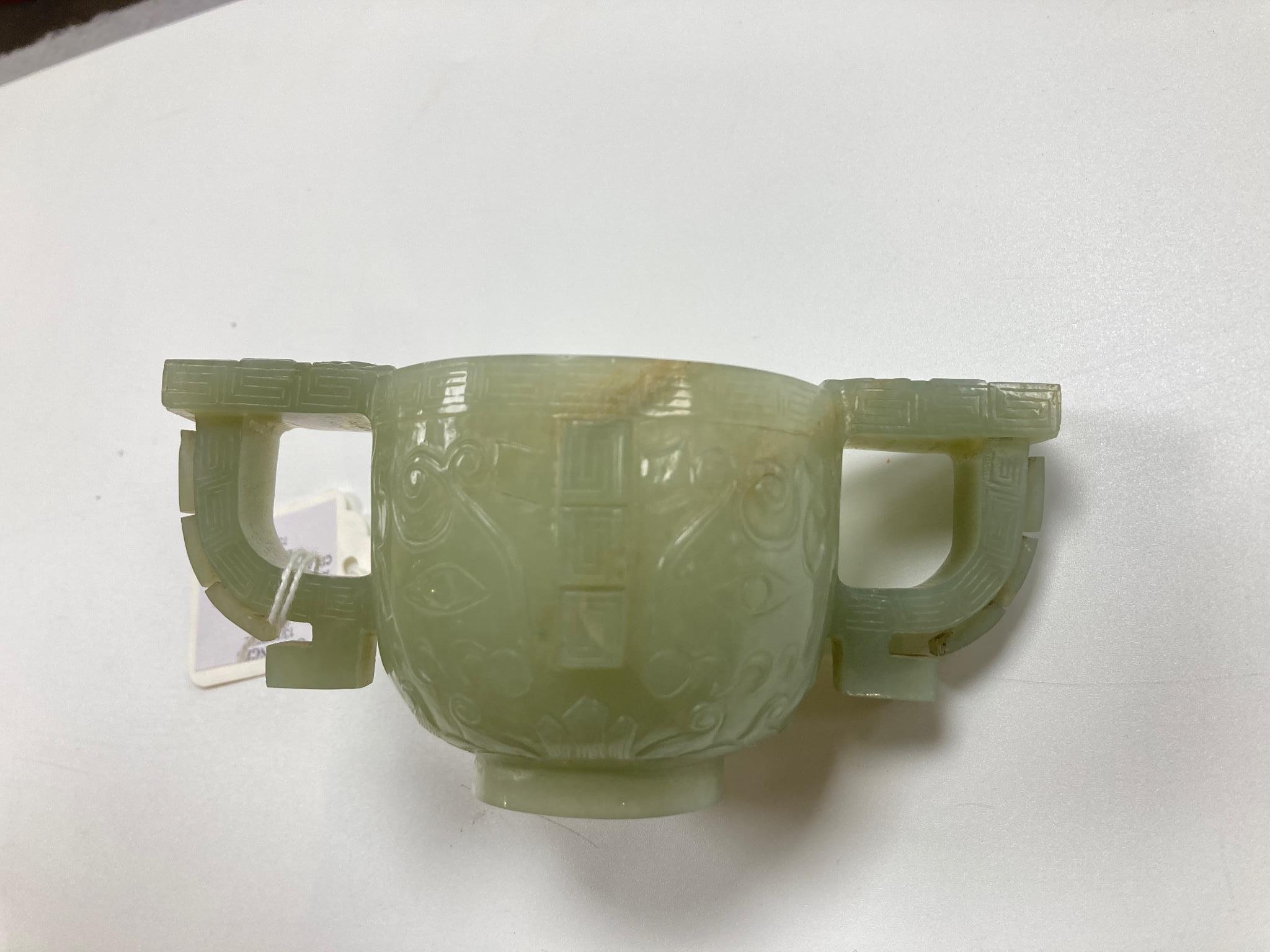 A Chinese archaistic celadon jade two handled cup, 17th century, 12.9cm across 6.1cm high, associated wood stand